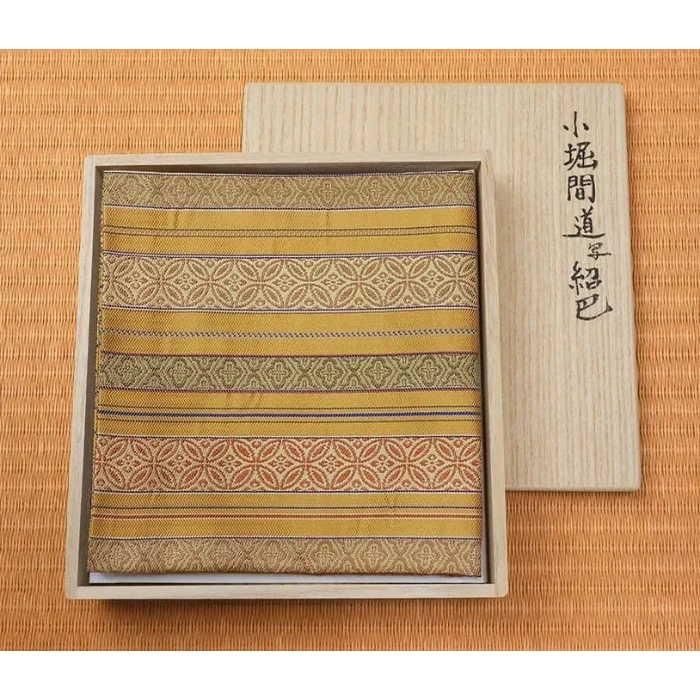 Traditional Japanese fabric with gold and brown patterns in a wooden box on a matching background