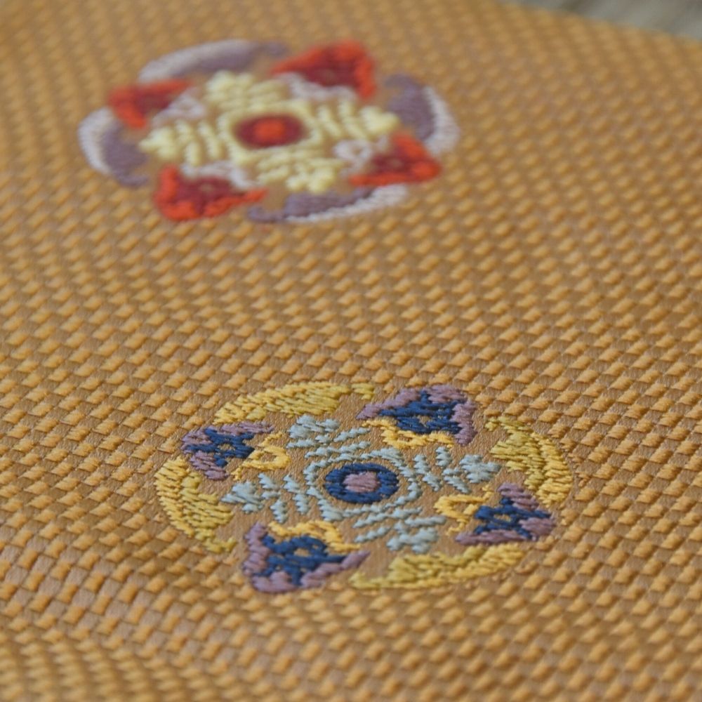 Close-up of embroidered designs on a yellow fabric surface