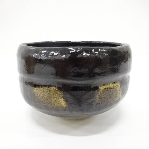 Black ceramic bowl with gold accents on a white background