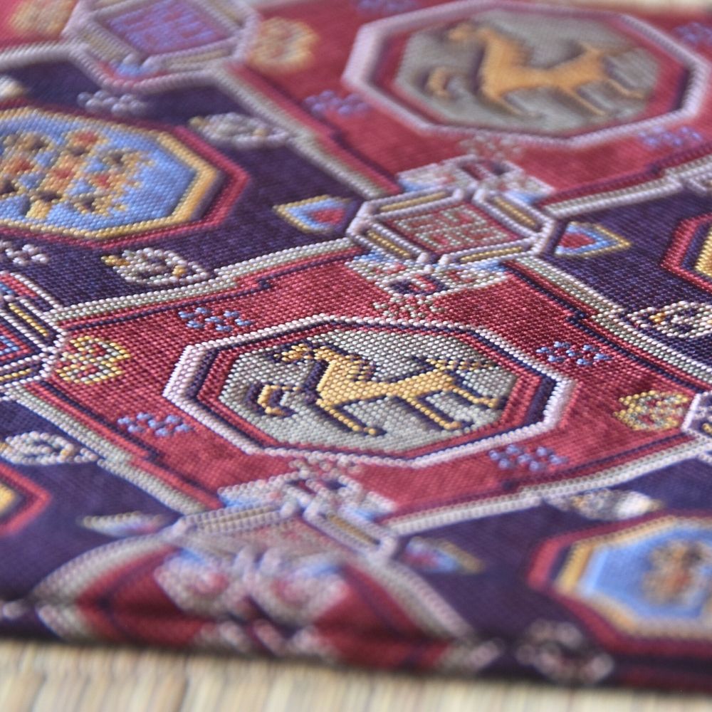 Close-up of a patterned fabric with geometric shapes and animal illustrations on a wooden surface.