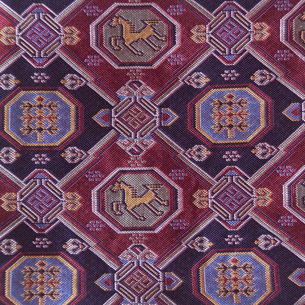 Close-up of a patterned fabric with geometric shapes and animal illustrations on a red background.
