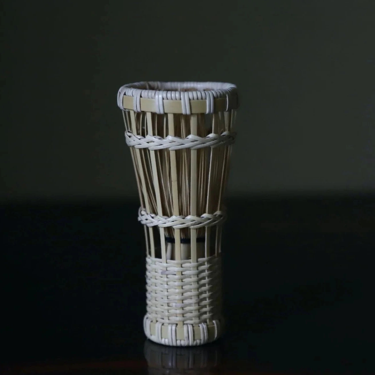 Woven vase on a dark surface with a dark background