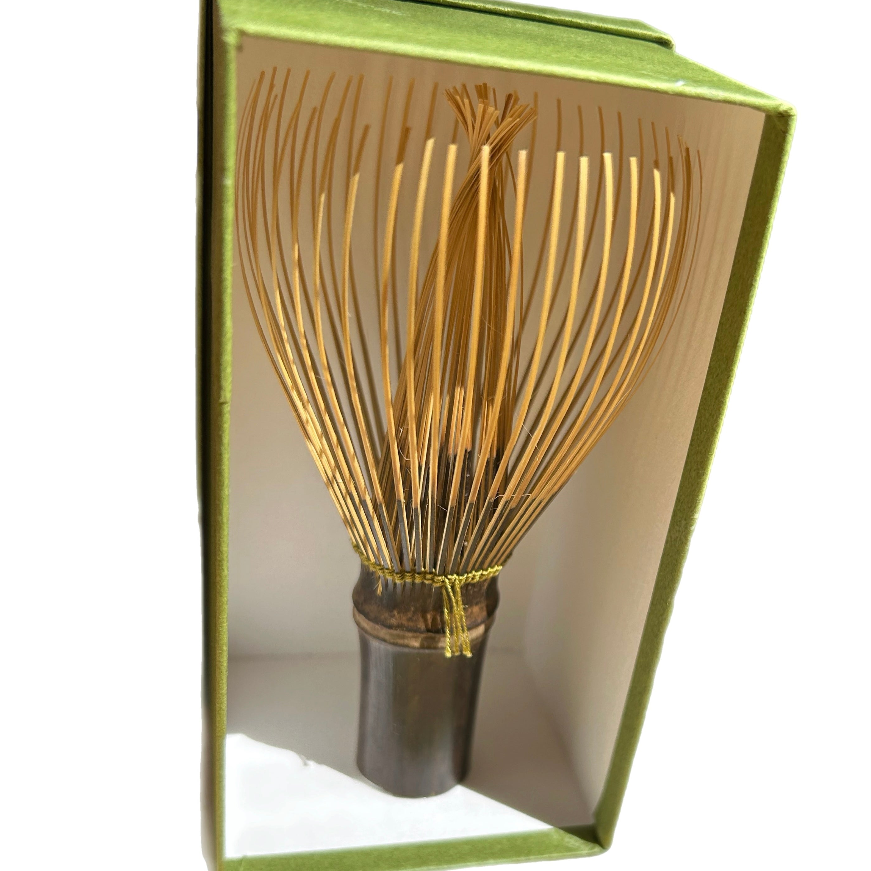 Tea whisk with wooden handle and bamboo bristles in an open book