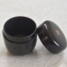 Black tea storage with lid on a light gray background