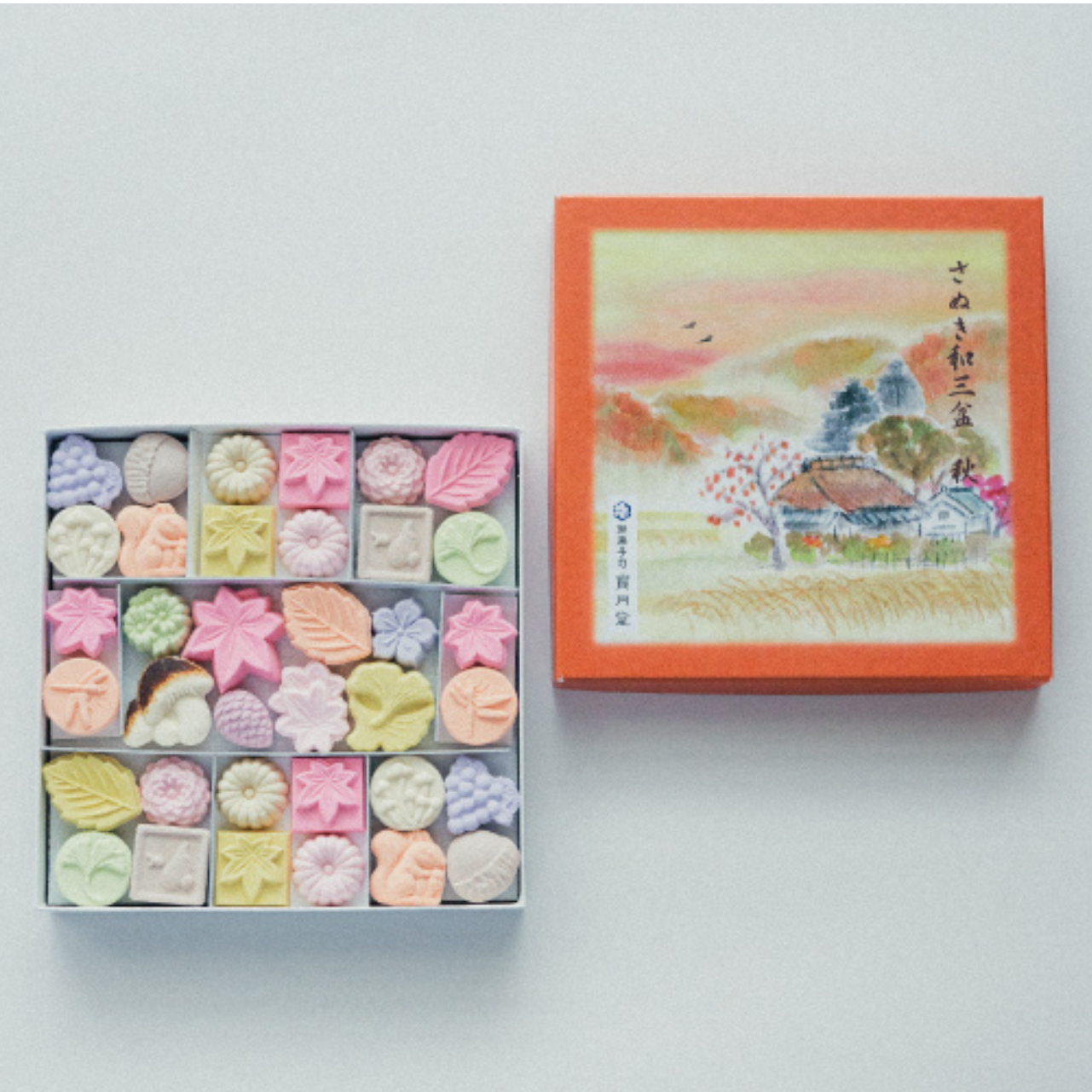 Box of assorted pastries with a decorative lid featuring an illustration on a white background