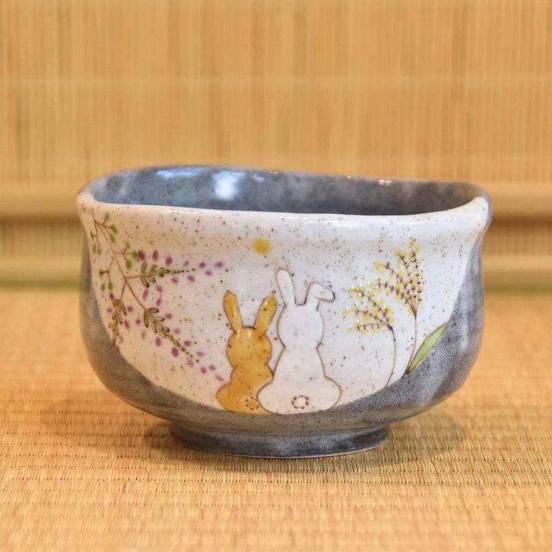 Ceramic bowl with rabbit design on a bamboo mat