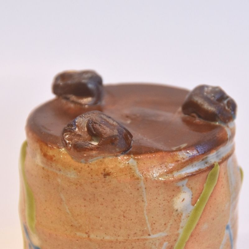 Ceramic pot with three small animal figures on top against a white background