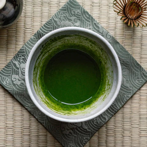 Green tea in a white cup on a textured mat