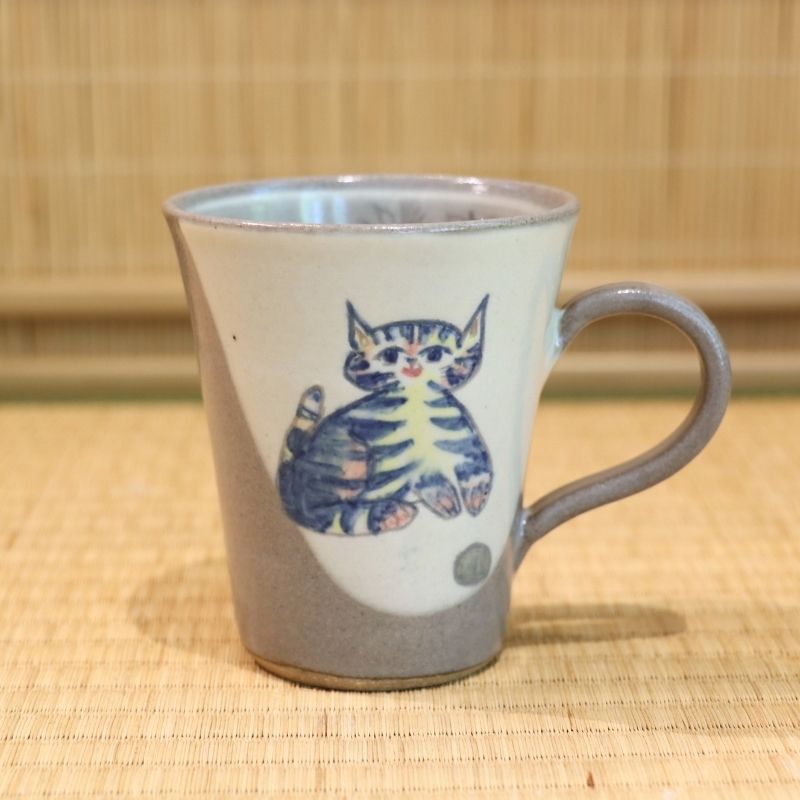 Ceramic mug with a cat illustration on a woven mat