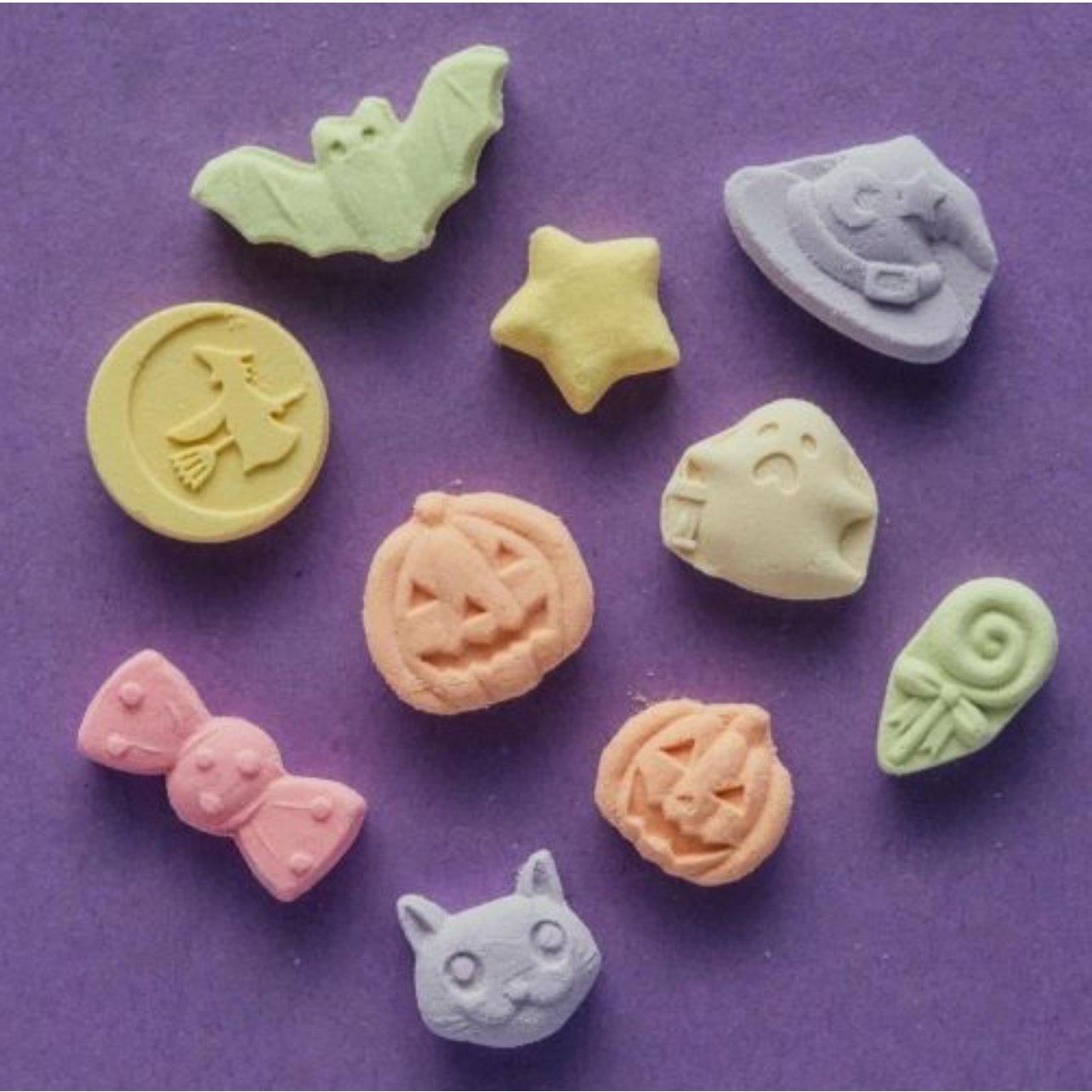 Colorful candy molds shaped like various objects on a purple background