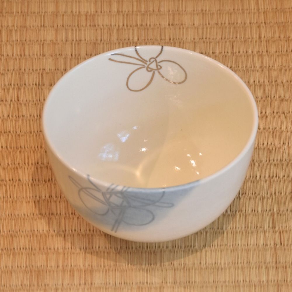 White ceramic bowl with floral patterns on a woven mat