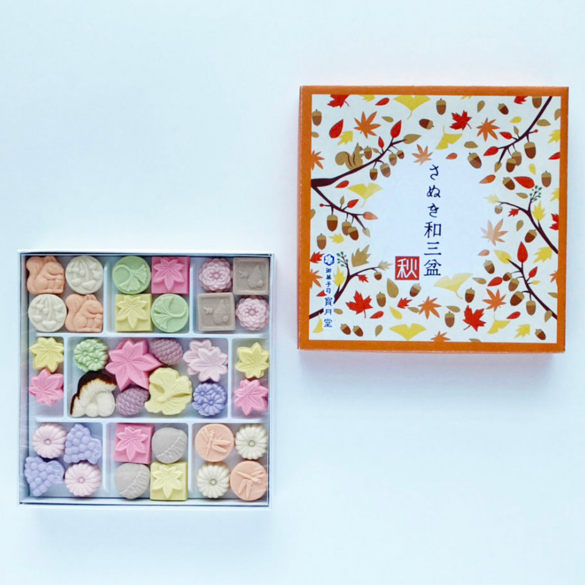 Box of assorted pastries with a decorative lid featuring an illustration on a white background