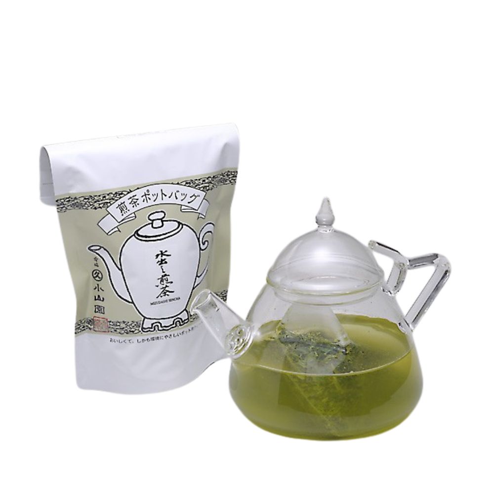 Glass teapot with green liquid and a white package with Japanese text on a white background