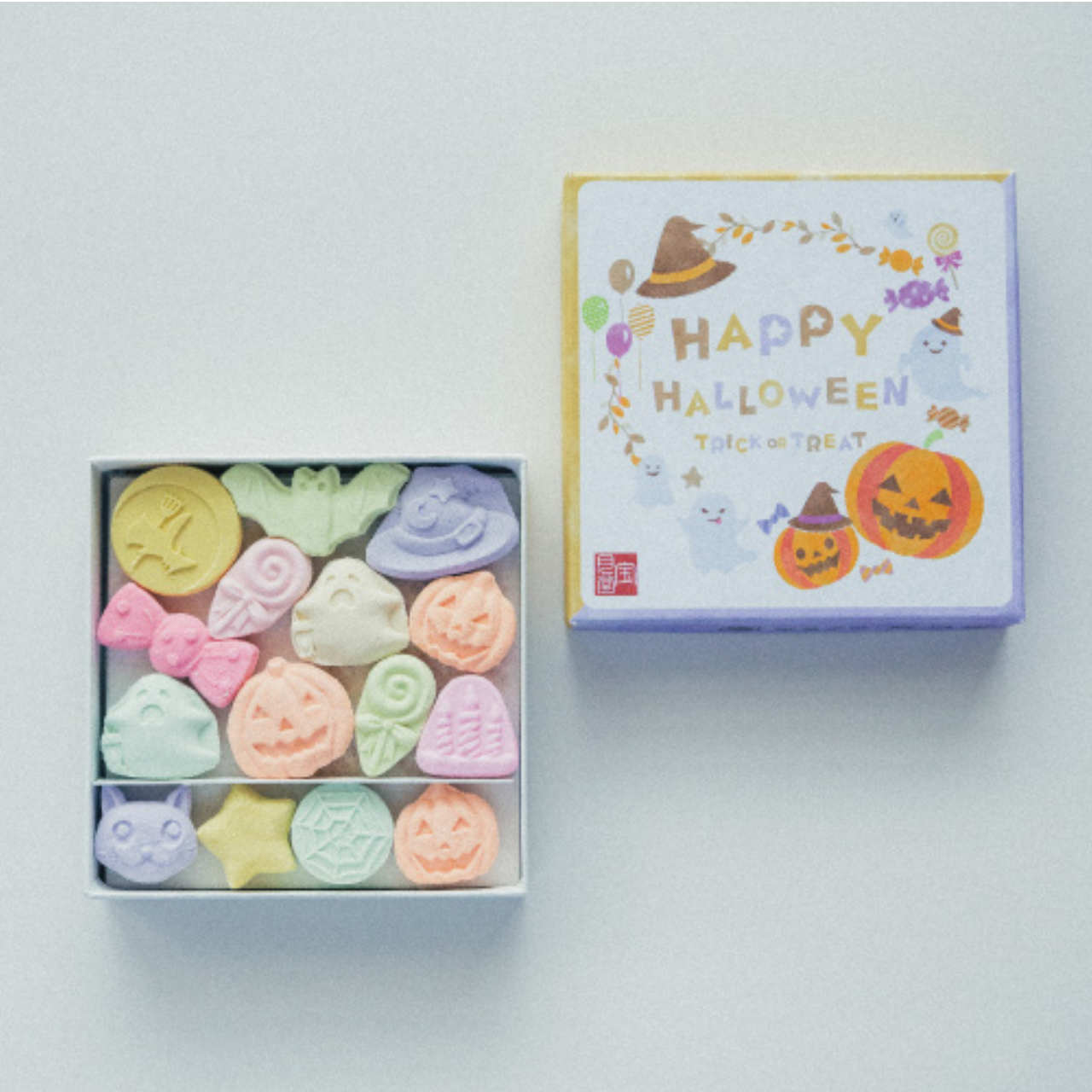 Box of colorful Halloween-themed bath bombs with a decorative box on a light background