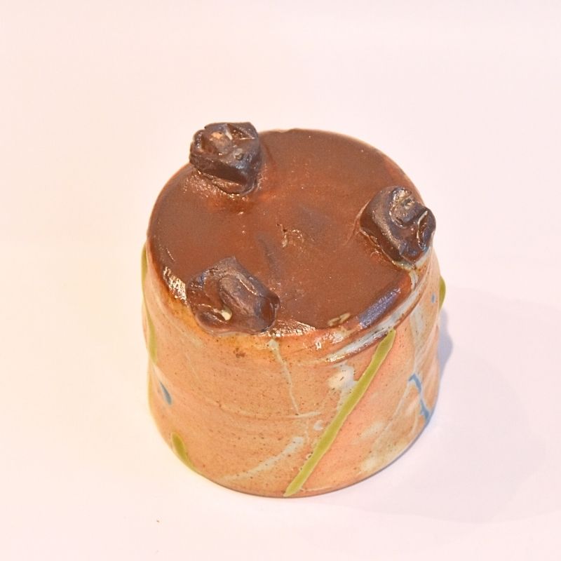 Cylindrical object with three protruding elements on a light pink background