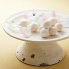 White ceramic cake stand with wasanbon higashi candy on a beige background