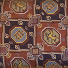 Close-up of a patterned fabric with geometric shapes and horse illustrations.