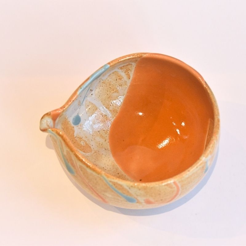 Ceramic bowl with orange and beige glaze on a gradient background