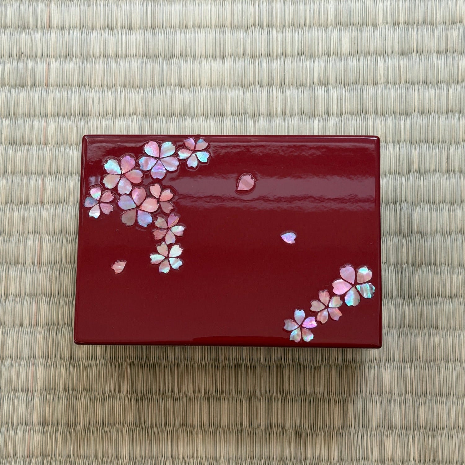 Red decorative item with floral patterns on a woven mat