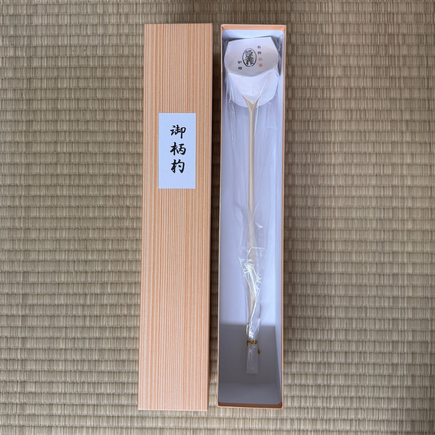 Traditional Japanese ladle in a wooden box on a textured brown background