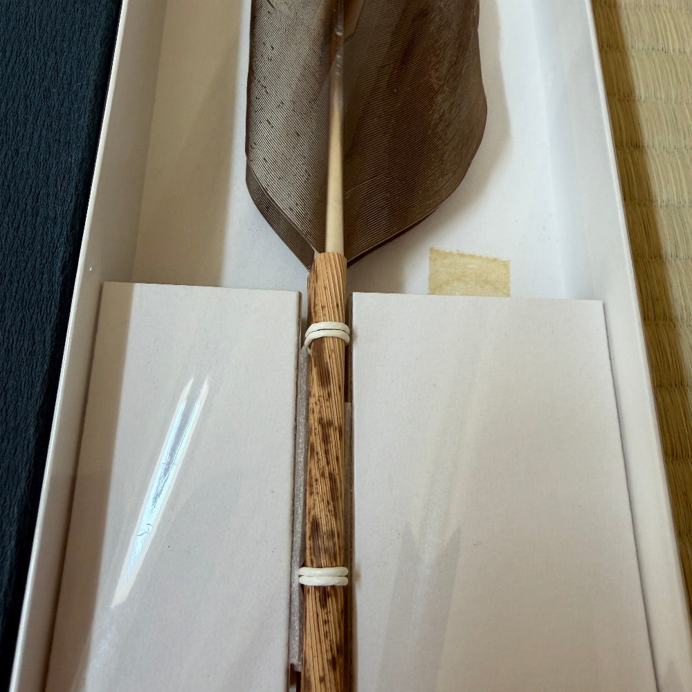 A traditional Japanese yamaboko wooden paddle with a dark brown carved blade and a striped natural wood handle, displayed inside its white presentation box.