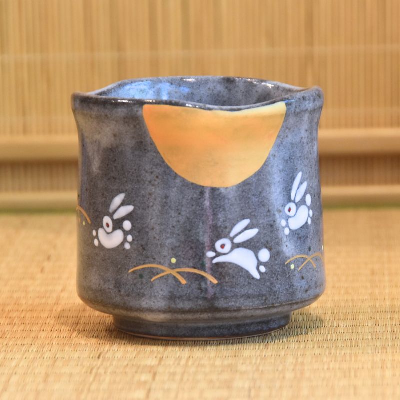 Ceramic cup with rabbit designs on a bamboo mat