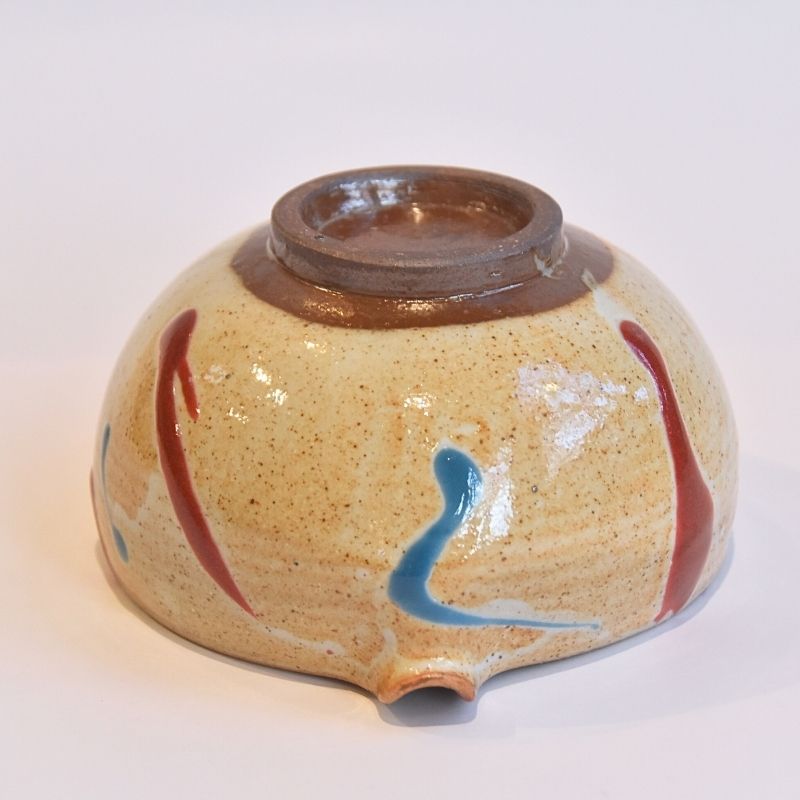 Ceramic bowl with brown interior and colorful exterior on a white background