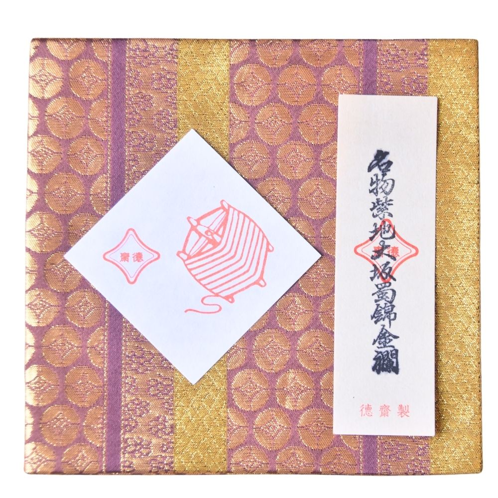 Decorative box with gold and purple patterns and a white label featuring text and a design.
