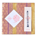 Decorative box with gold and purple patterns and a white label featuring text and a design.