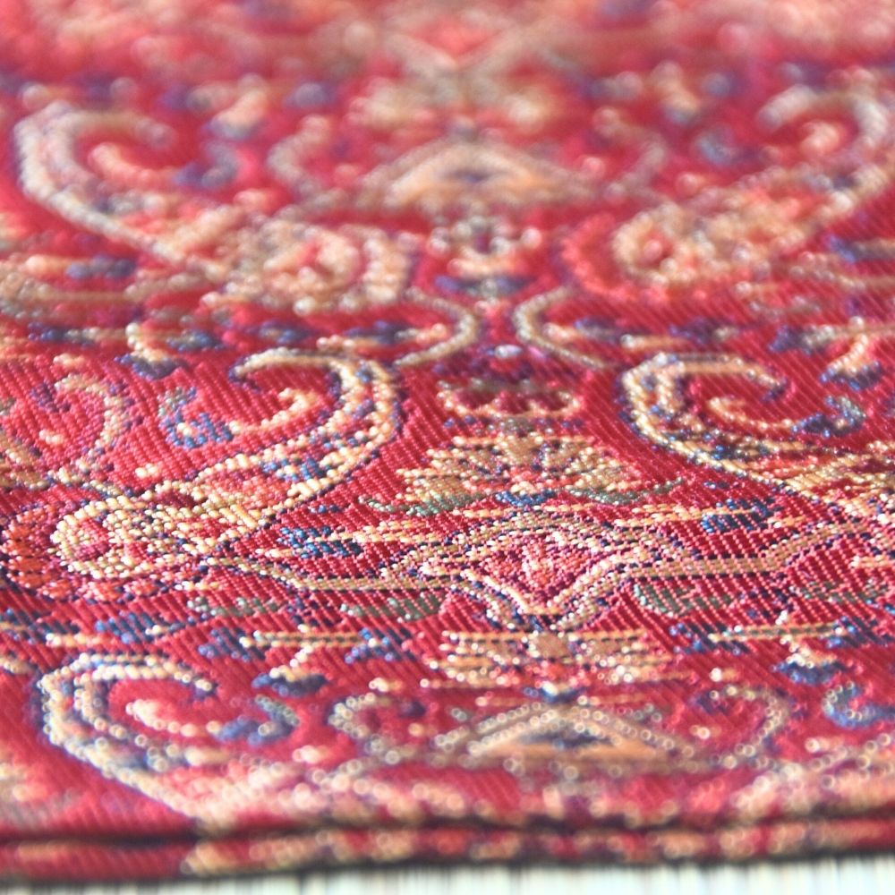 Close-up of red fabric with intricate gold and purple patterns