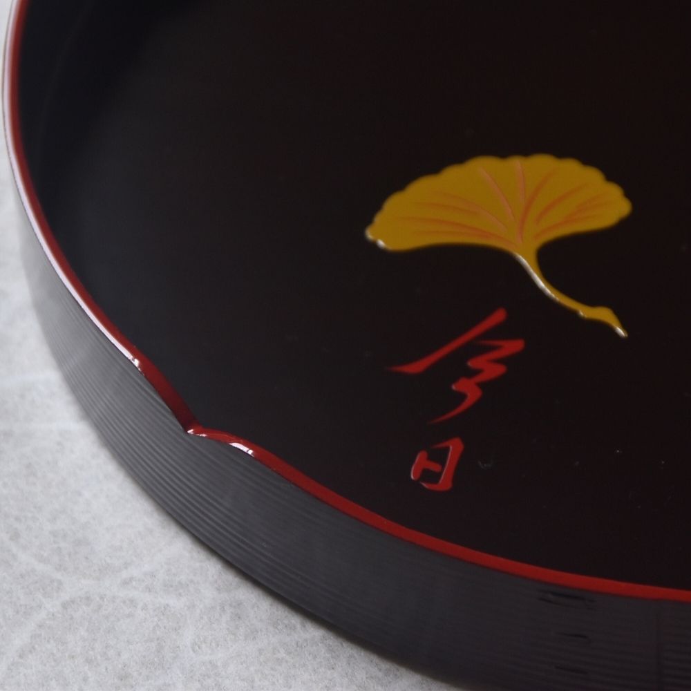 Black dish with a yellow leaf and red text on a gray background