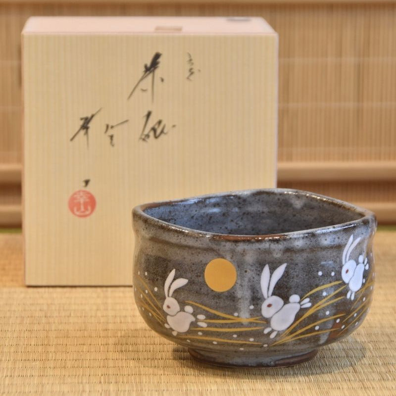 Ceramic bowl with bunny illustrations on a wooden surface, with its box in the background