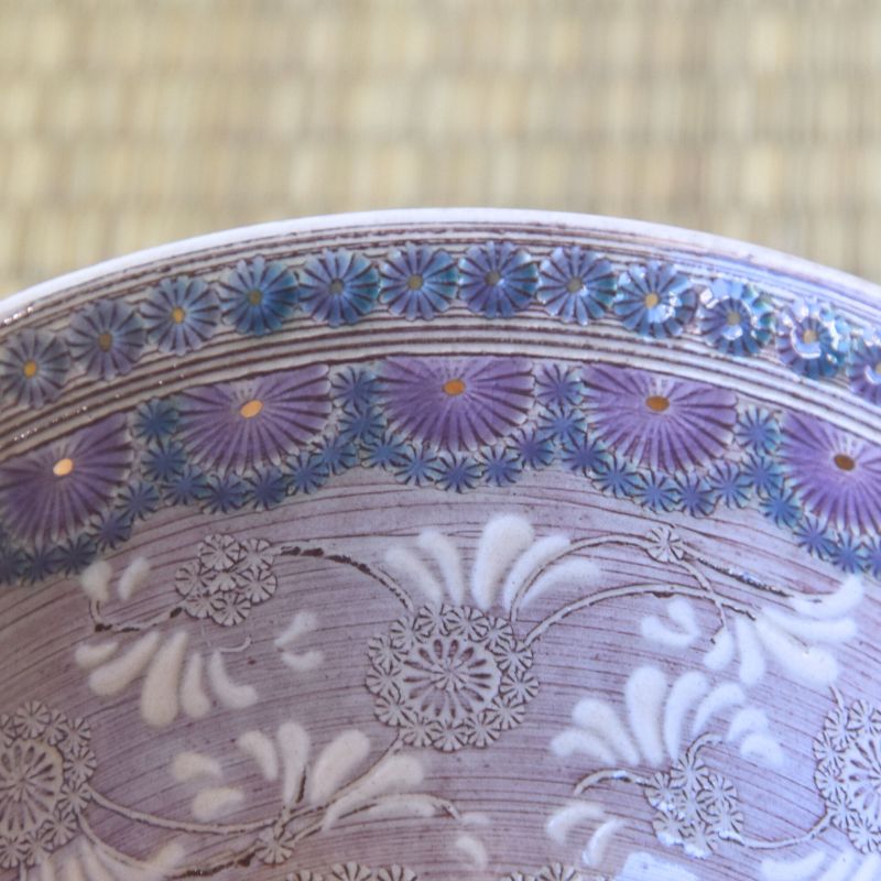 Close-up of a ceramic bowl with floral patterns on a textured beige background