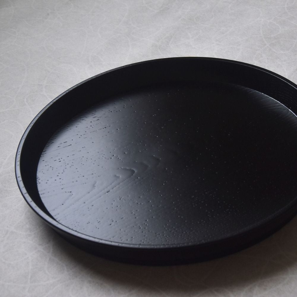 Black round tray on a gray textured surface