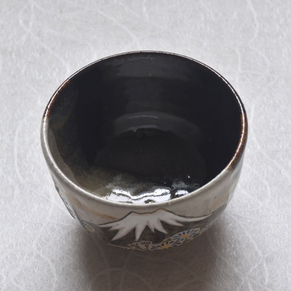 Ceramic cup with floral design on a textured white surface