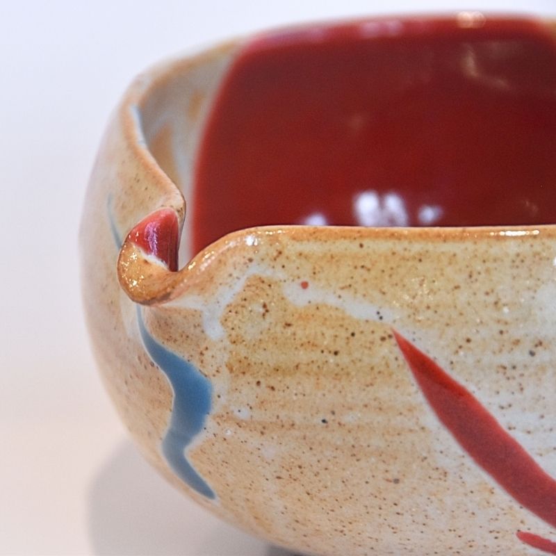 Close-up of a ceramic bowl with red interior and beige exterior