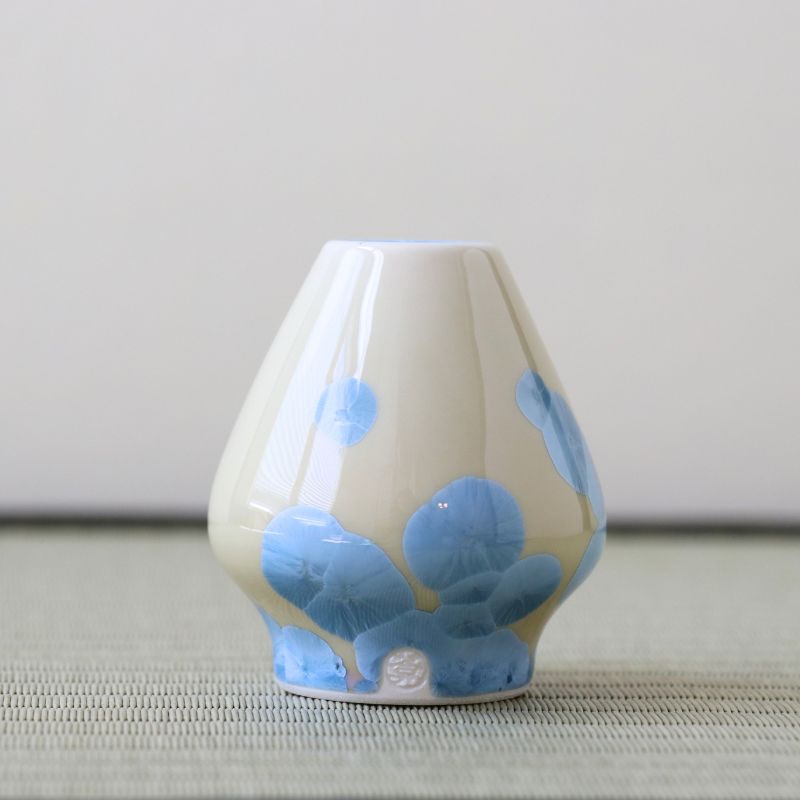Matcha whisk stand with blue floral patterns on a neutral background