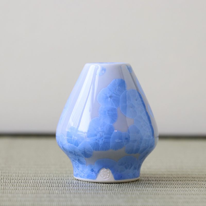 Blue and white ceramic matcha whisk stand on a neutral background