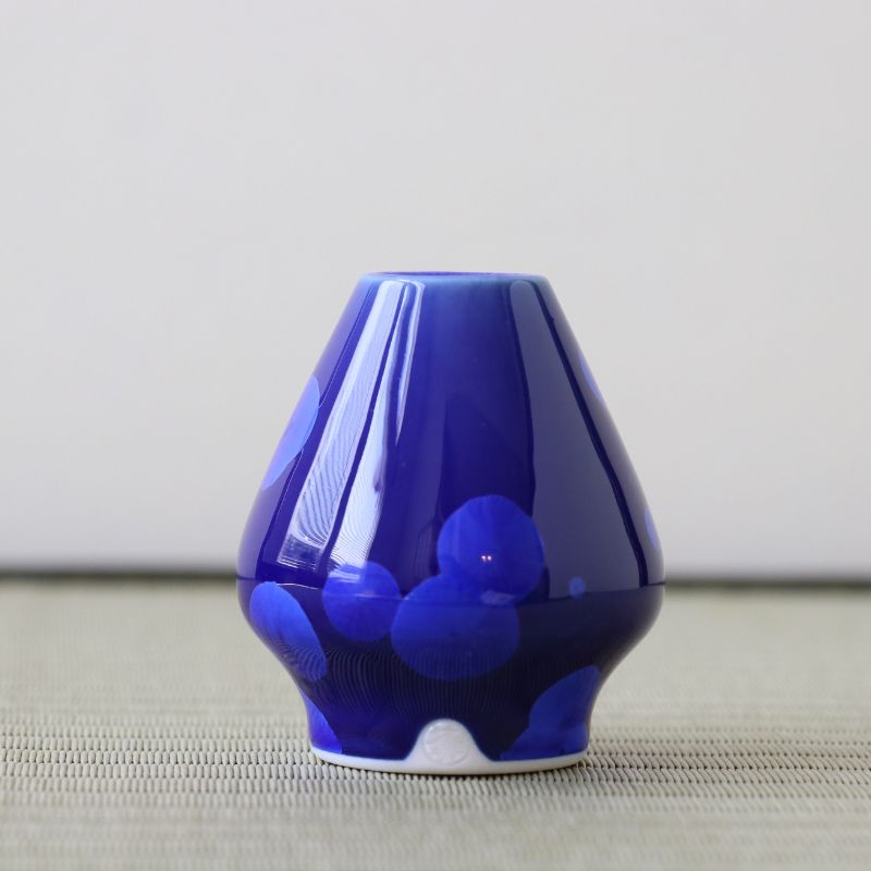 Matcha whisk stand holder on a textured surface with a neutral background