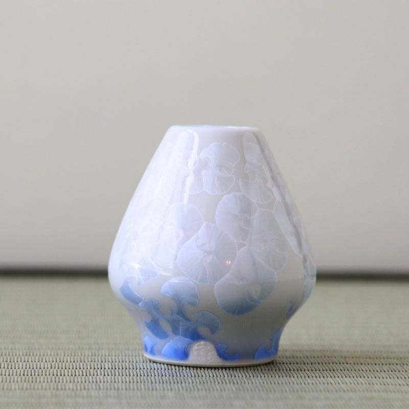 White textured vase with blue accents on a light gray surface