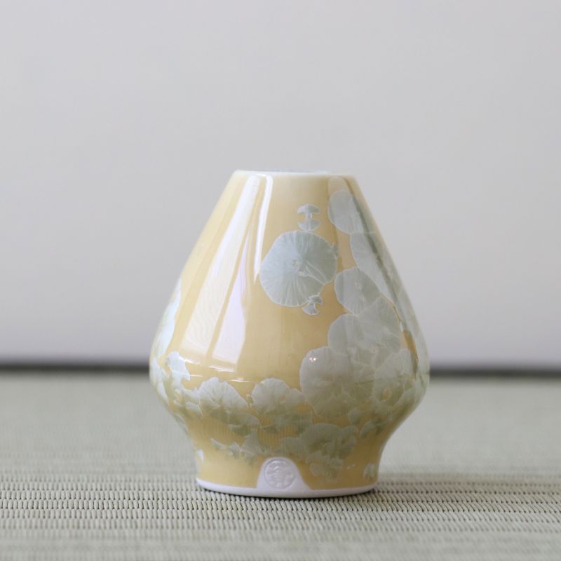 Yellow ceramic vase with white floral patterns on a neutral background