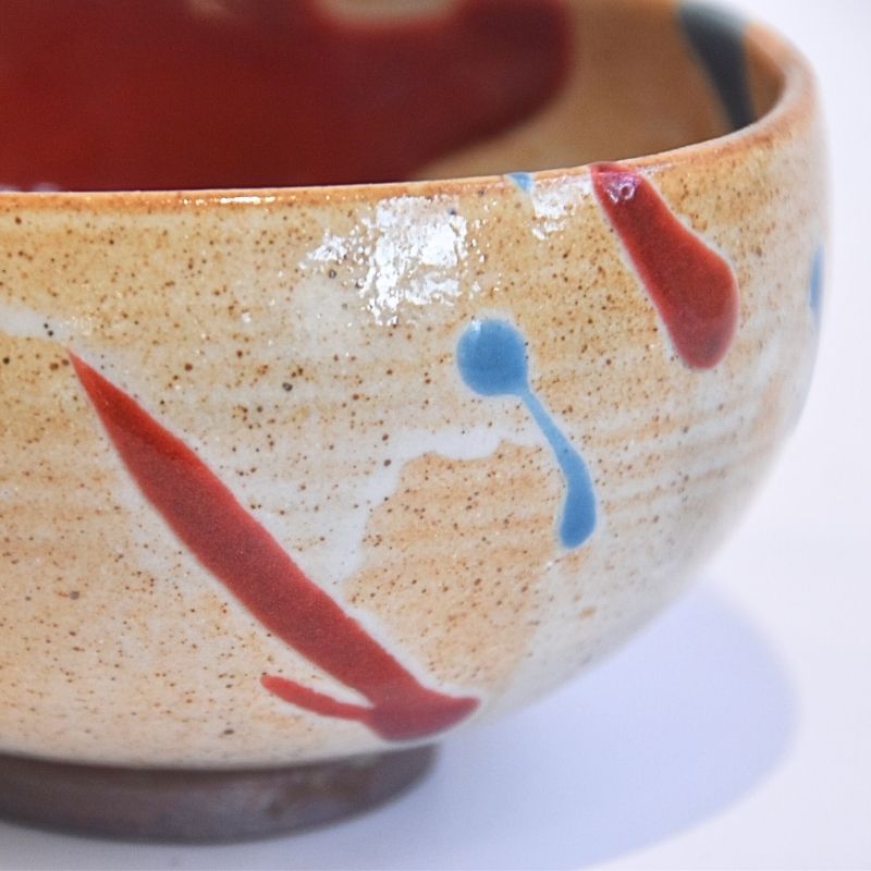 Ceramic bowl with red and blue abstract designs on a white background
