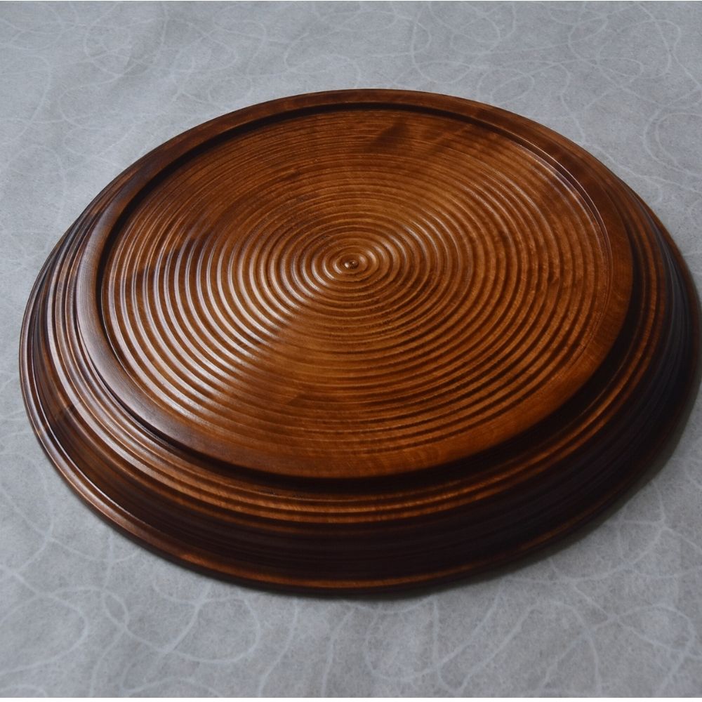 Wooden plate with concentric circle pattern on a gray background