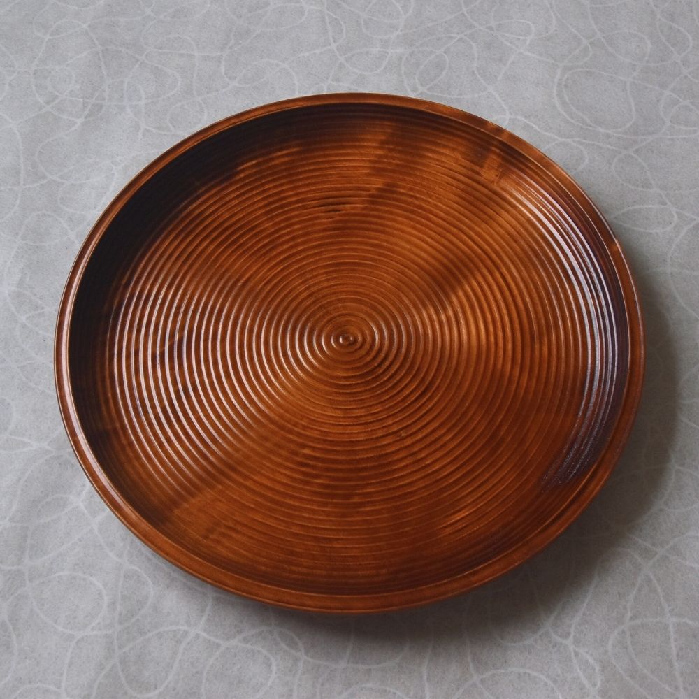 Wooden plate with concentric circle pattern on a gray textured background