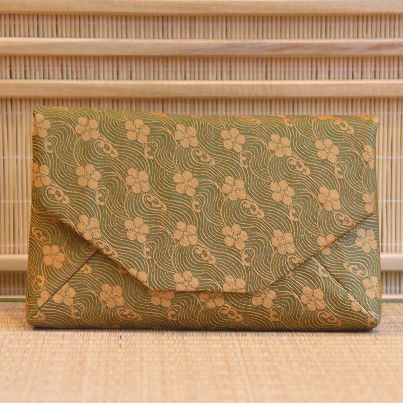 Green floral patterned clutch bag on a wooden surface