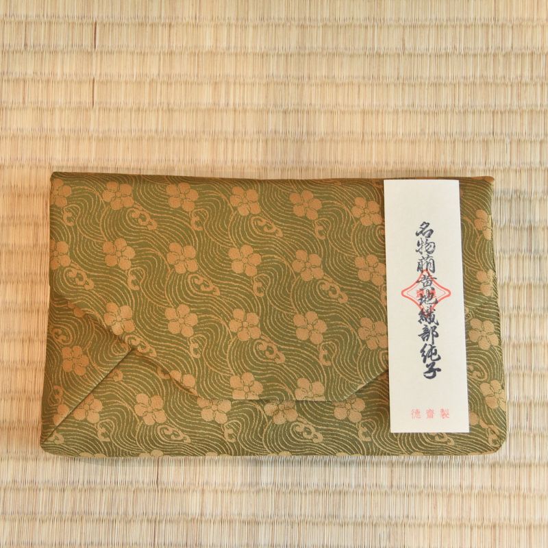 Green patterned envelope with a white label on a woven mat background