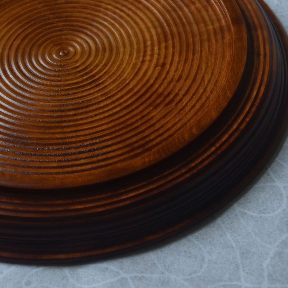 Stack of wooden plates with concentric circular pattern on a light gray background