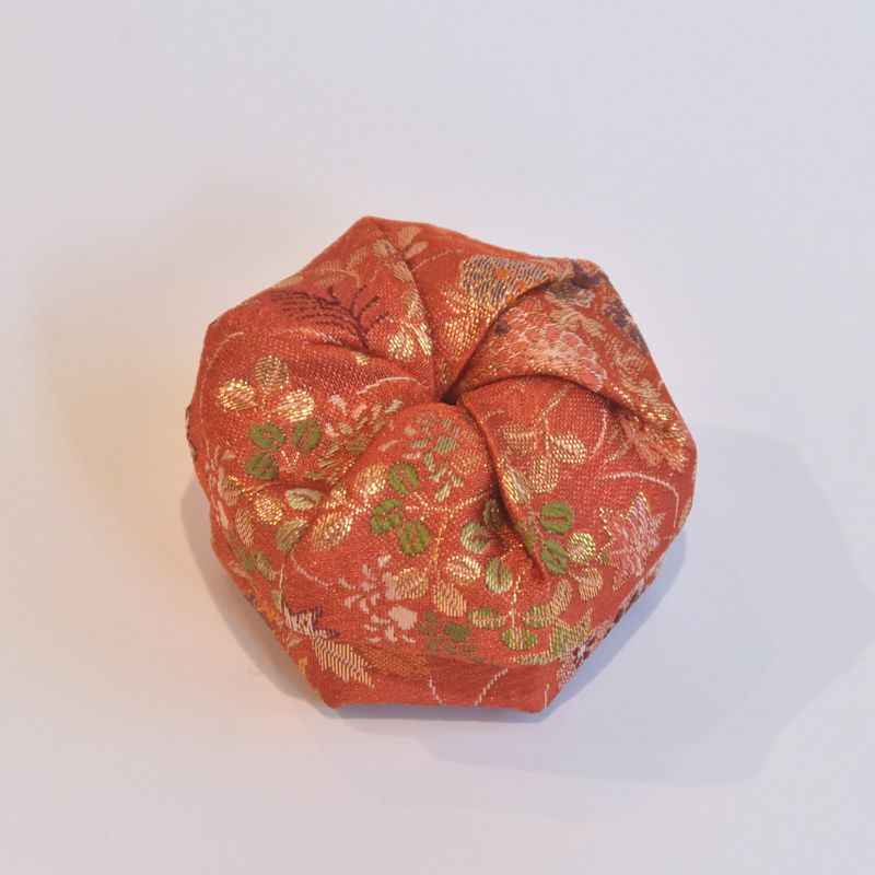 Orange fabric wrap with gold and green floral patterns on a white background