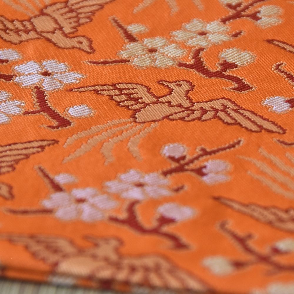 Close-up of fabric with bird and floral pattern on an orange background