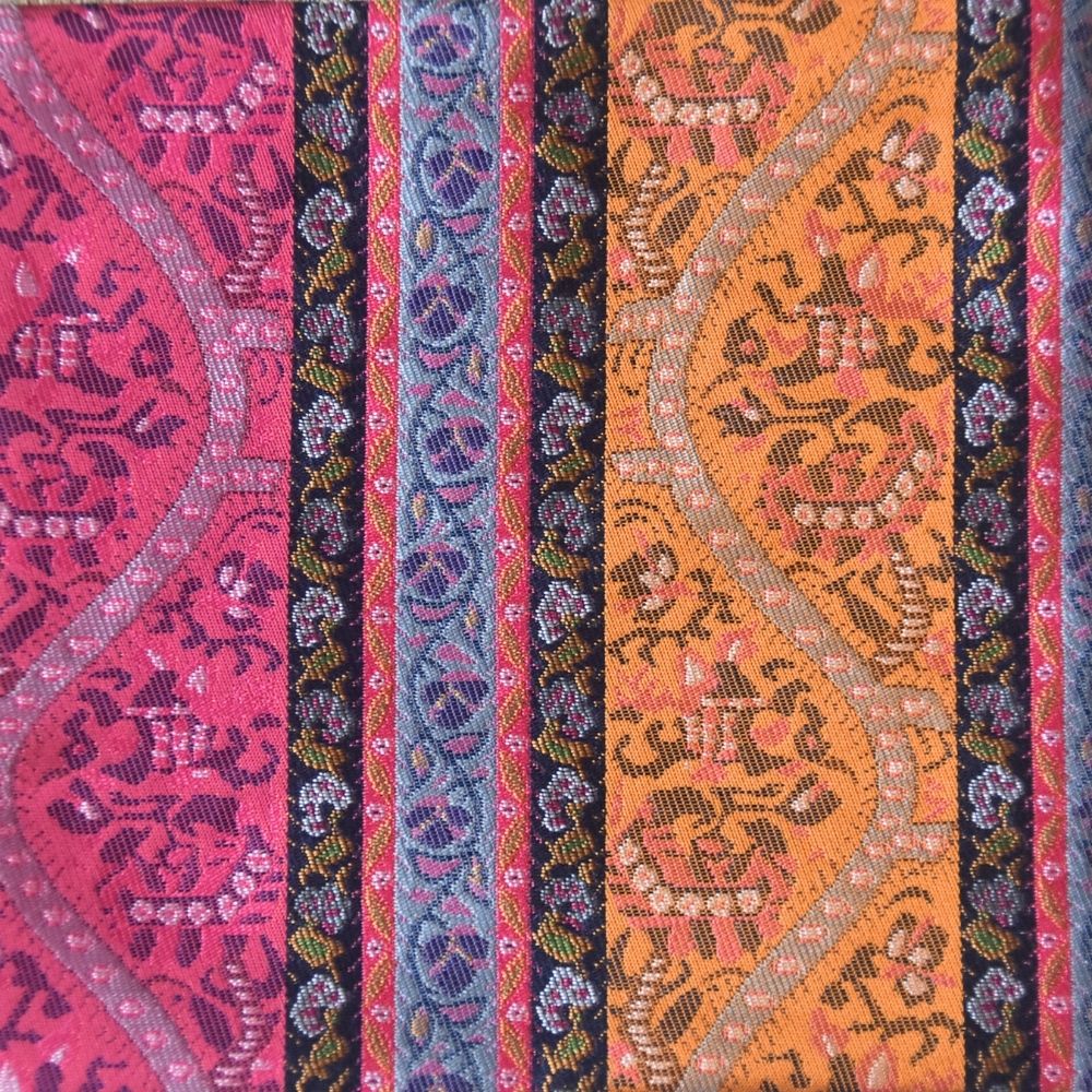 Colorful fabric with intricate patterns in pink, orange, and blue.